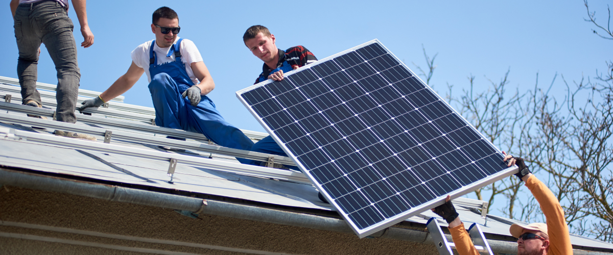 Roofers installing solar panels on top of a home.